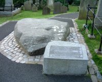 Saint Patrick's Grave: INSCRIPTION [Saint Patrick was born in Britain. At sixteen he was sold into slavery. He escaped to France, but one night in a dream he heard the voice of the Irish calling him back. How Patrick answered that call and brought Christianity to Ireland is one of the most splendid chapters of our history. According to tradition the remains of Saint Patrick with those of Saint Brigid and Saint Columba who was also known as Columcille, were reinterred on the site by John de Courcy in the 12th Century thus fulfilling the prophecy that the three saints would be busied in the same place.]  The large granite boulder was placed in the graveyard of Down Cathedral in 1900 by F.G. Bigger of the Belfast Naturalist Field Club. On the stone is carved the name PATRIC and a cross. It is a memorial, not a tombstone. Photo - Pat Devlin 	CLICK FOR LARGER PICTURE